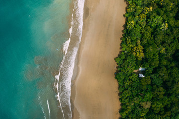 Aerial Drone View of a tropical beach in Costa Rica. Sand and water surrounded by lush rainforest