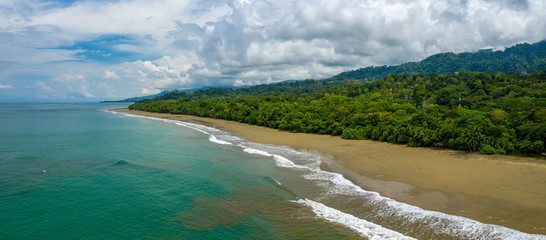 Aerial Drone View of a tropical beach in Costa Rica. Sand and water surrounded by lush rainforest