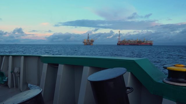 FPSO tanker vessel near Oil Rig platform. Offshore oil and gas industry. Flare is burning with smoke. View from supply vessel.