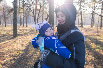 little toddler baby sits in the sling ergorace father, carrying child in an upright position without load on the spine