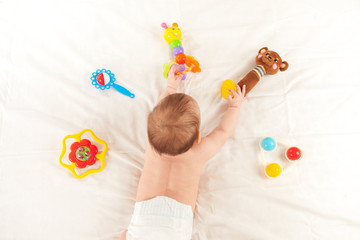 baby newborn lying on his stomach on the bed among the toys, the problem of choice in children, early development of children