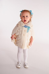 little girl in a woolen knitted wrap - poncho on a white background