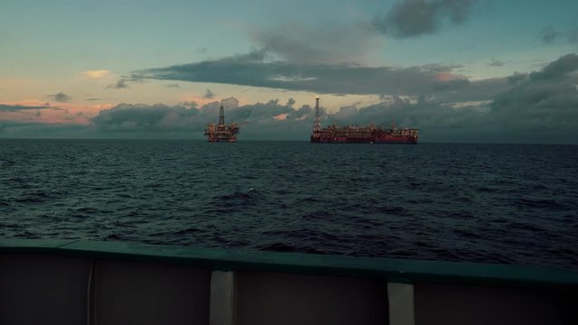 FPSO tanker vessel near Oil Rig platform. Offshore oil and gas industry. Flare is burning with smoke. View from supply vessel.