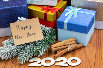 Fir branches, gift boxes, cinnamon, figures 2020,  congratulation note on a wooden background