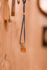 Jar with aromatic oil, suspended on a cord with wooden decor, on a yellow background. Copy space.