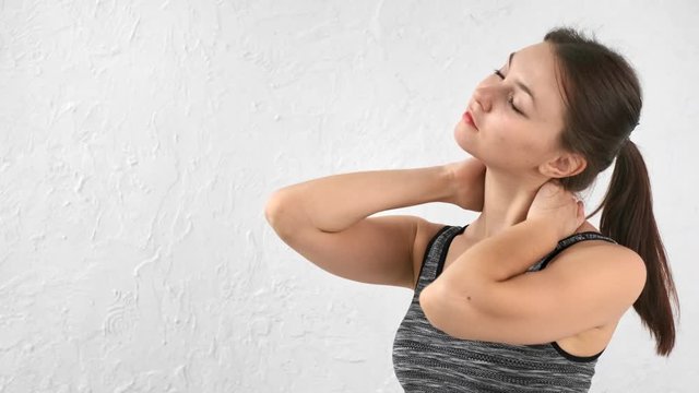 Relaxed sports female turning head stretching neck isolated at white studio background