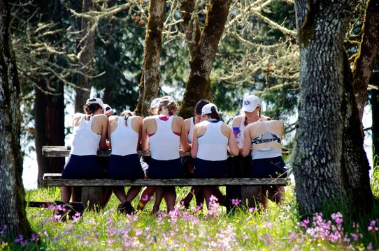 A crew team goes through a pre race visualization exercise surrounded by trees and wildflowers 