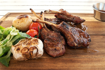  Grilled meat, lamb ribs with spices, vegetables and garlic on a wooden background