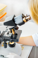 The lab technician looks into the microscope and records and analyzes the blood.
