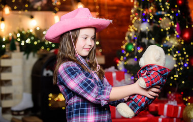 Happy new year. cowgirl child with toy bear. Xmas tree. Happy holiday. Little girl in cowboy hat. Happy christmas. Santa claus little girl. Chriatmas interior. Christmas time. Best present
