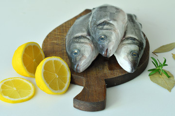 Raw fish seabass. Raw fish fillet with spices, herbs, lemon and salt on wooden board ready for cooking, food background. food concept. Mediterranean seafood