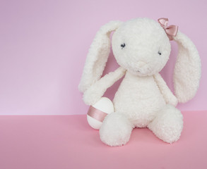 Easter white bunny rabbit with white egg on pink background. 
