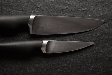 Modern Kitchen Knives Set on Dark Stone Background. Black knives on a black background. Chef's Knives Concept.
