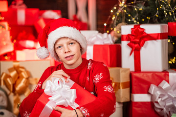 Fototapeta na wymiar Intrigued cute santa. Child little happy boy find gifts near christmas tree. Gifts shop. Kid santa hat christmas gift boxes. Merry christmas. Beauty of winter. Leisure and activity. Boxing day