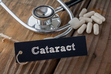 Cataract written on label tag with pills and Stethoscope on wood background