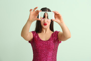 Beautiful woman taking selfie on color background