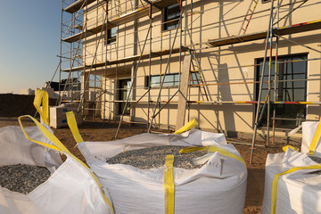 Einger&uuml;steter Neubau. Davor stehen S&auml;cke mit Baumaterial