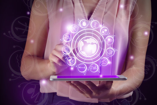 Female astrologist using tablet PC on dark background