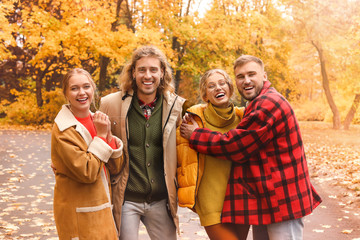 Happy young friends resting together in autumn park