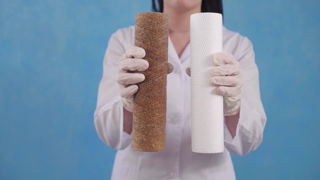 woman holds a used and clean reverse osmosis cartridge water filter on a blue background