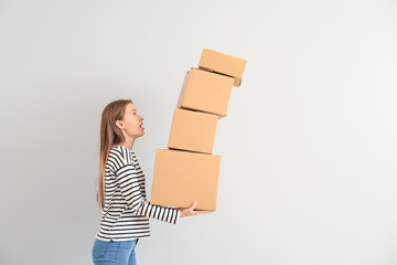 Bothered woman dropping cardboard boxes on light background