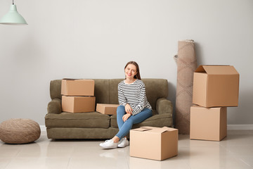 Happy young woman with moving boxes in new house