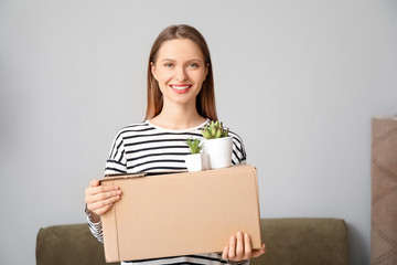 Happy young woman with belongings in new house