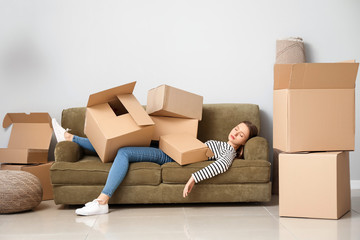 Sleeping woman with heap of moving boxes lying on sofa in new house