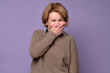 Middle age woman wearing sweate laughing and embarrassed giggle covering mouth with hands, gossip...