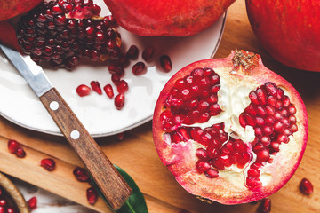 Tasty pomegranate with knife on wooden board