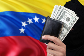 Venezuela security and crime concept. Black criminals wear a head yarn, hold a dollar banknotes on...