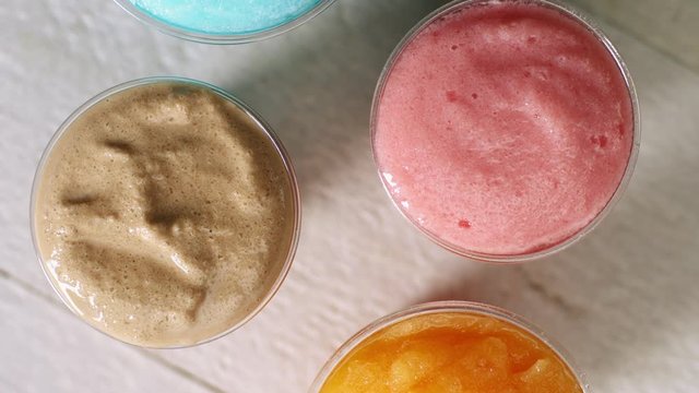 Lemon strawberry chocolate and blueberry slush cup top view rotate on table top 