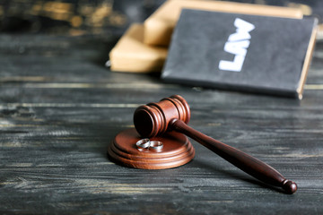 Obraz premium Judge's gavel and rings on wooden background. Concept of divorce