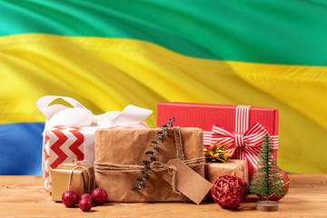 Gabon new year celebration theme. Wrapped christmas gifts on waving national flag background. Merry...