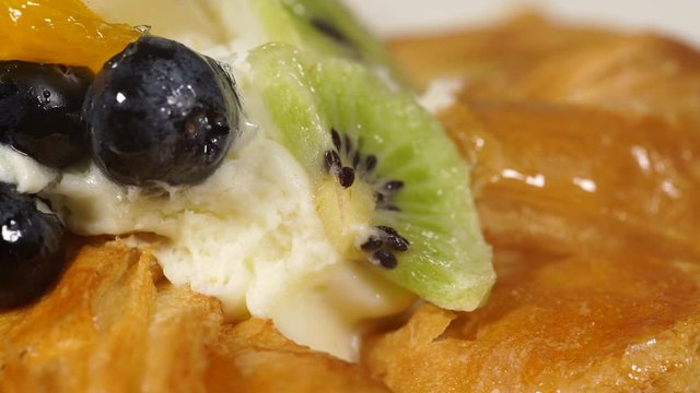 Close up puff pastry pie decorated with fresh blueberry and fruit slices - kiwi, grapes, ananas. Delicious dessert
