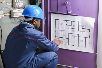 African-American electrician performing wiring in distribution board