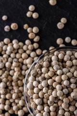 white peppercorns in glass bowl on stone background
