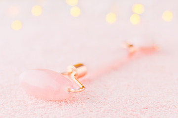 real rose quartz facial roller closeup on pastel pink background with bokeh, soft focus
