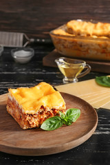 Plate with prepared lasagna on wooden table