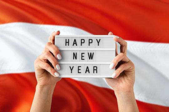 Austria New Year concept. Woman holding Happy New Year sign with hands on national flag background. Celebration theme.