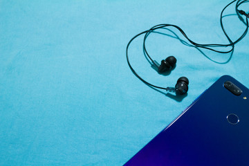 blue smartphone with headphones on a blue background