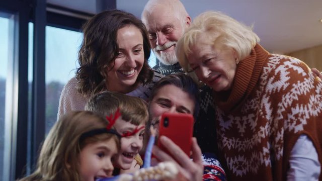 Adorable big caucasian family with kids taking common selfies on smartphone in holiday atmosphere on Christmas Eve. New Year family celebration.