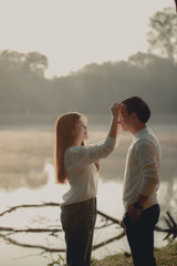 An Asian girl touching her boyfriend's head at beside the lake on morning.