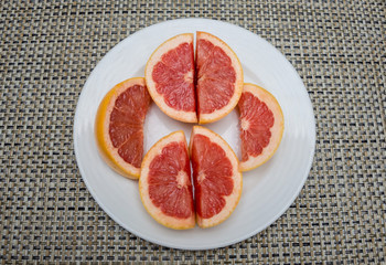 Cutted grapefruit on a white plate, top view.