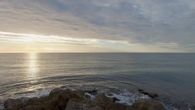 Footage of sea waves splashing on the shore in Sitges, Spain. The environmental sound is present.