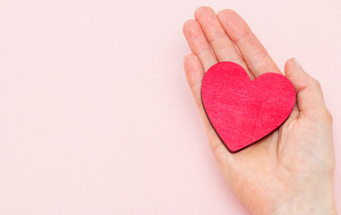 Obraz premium man holds a red heart in his palms on a pink background