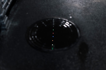 Reflection of multi-colored lights in a puddle on the sewer manhole in the city at night.