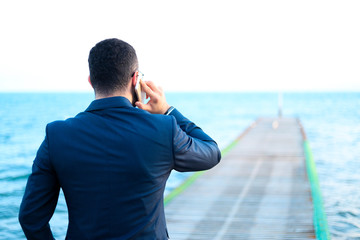 businessman having a call in front of the sea
