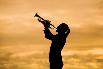 silohuette of man playing trumpet  against yellow background