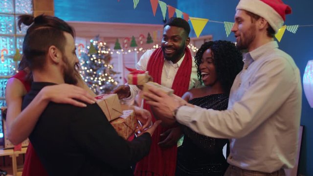 Happy New Year. Happy euphoric young people greeting their friend loading with Christmas gifts having fun time enjoying gorgeous holiday celebration. Fun boxing day.
